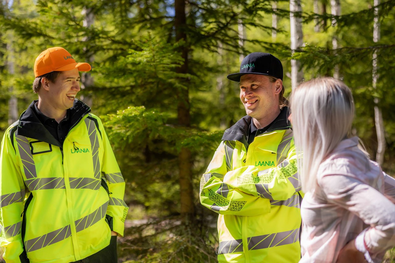 Metsäasiantuntijat juttelevat metsänomistajan kanssa keväisessä metsässä.