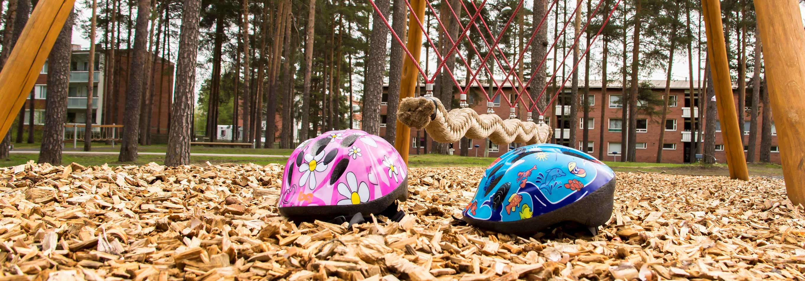 Lasten kypärät leikkipaikalla hakkeen pinnalla.