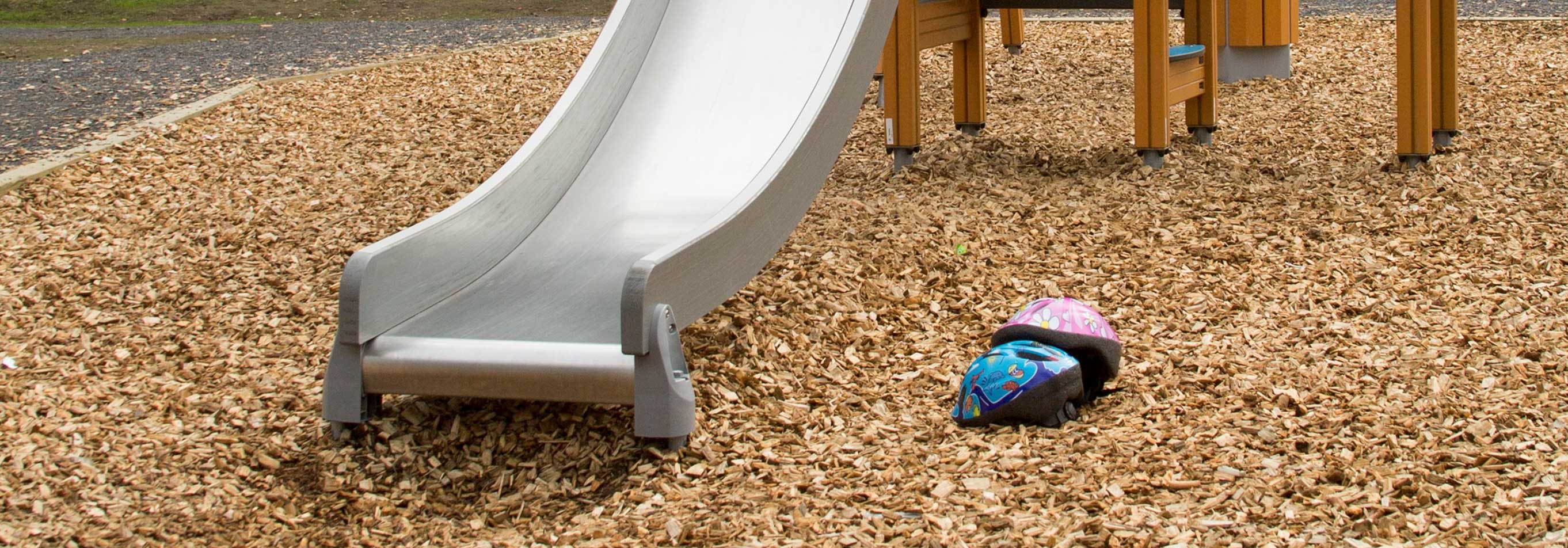 Liukumäki, jonka alla on leikkipaikkahaketta.