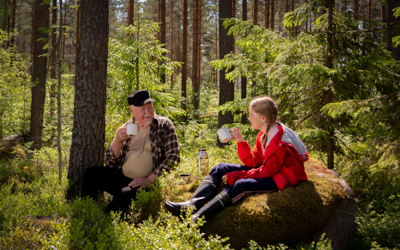 Pappa ja tyttö istuvat metsässä ja pitävät evästaukoa.